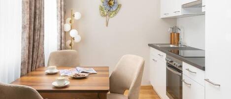 A modern kitchen with white cabinets, a wooden dining table, and a chandelier.