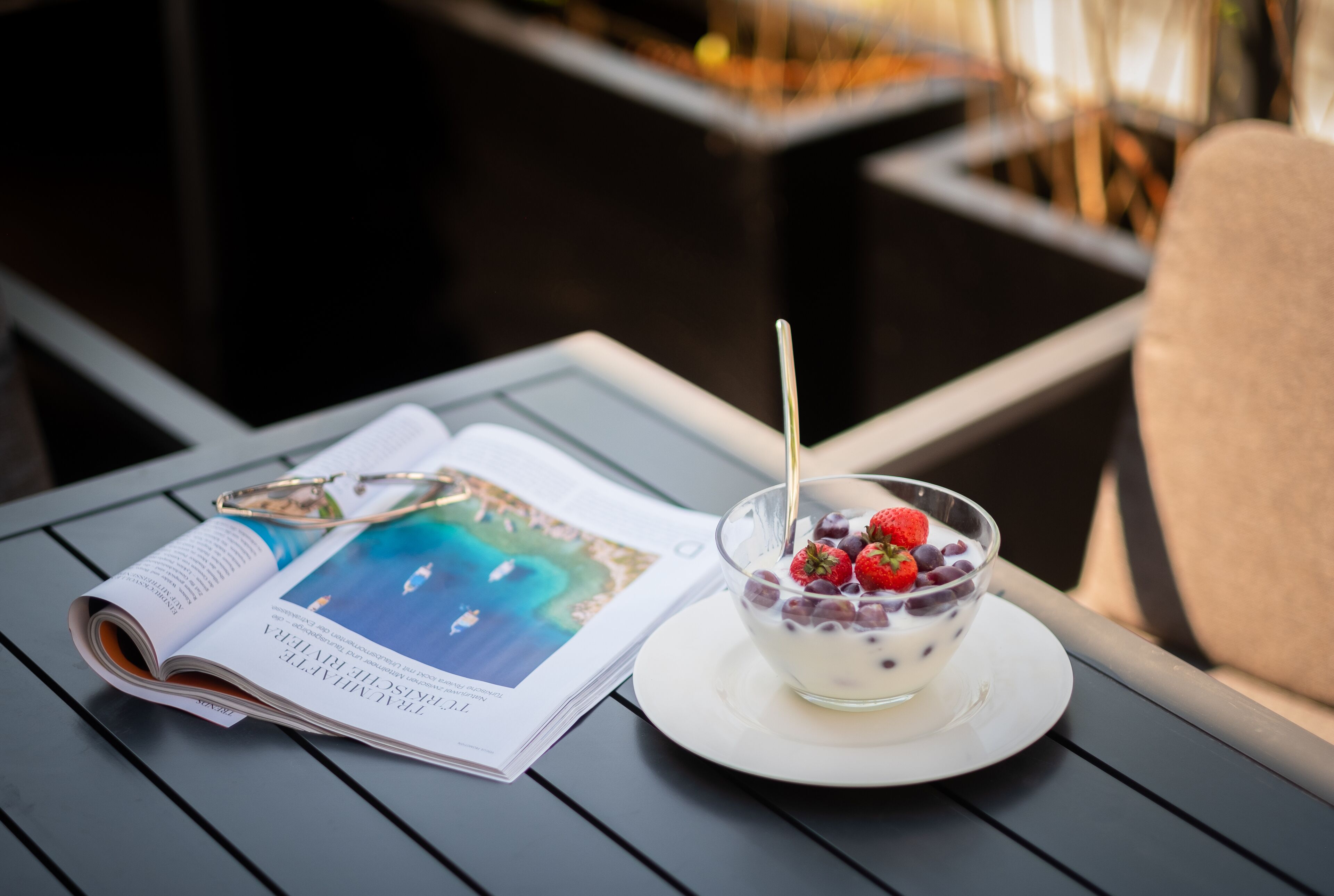 A magazine on a table with a bowl of yogurt topped with berries.