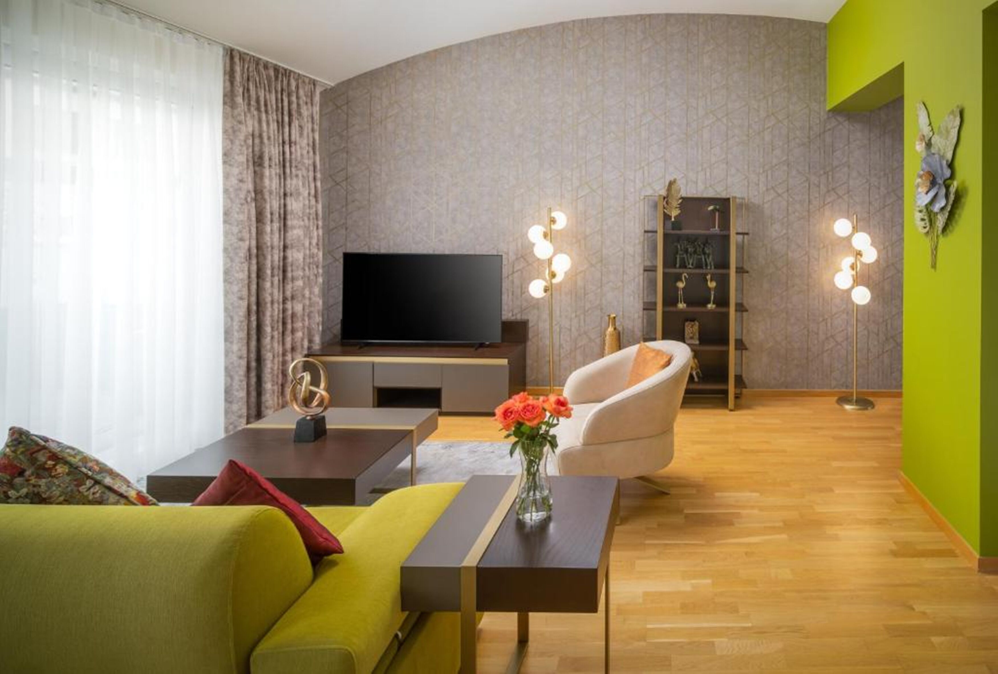 Una sala de estar moderna con una televisión de pantalla plana, un sofá, una mesa de centro y una estantería.