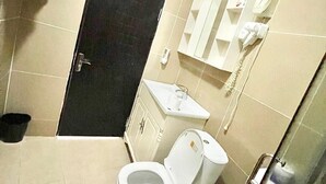 A bathroom with a toilet, sink, and a black door. - Seaside Suites and Hotel Room #101 (Freetown)