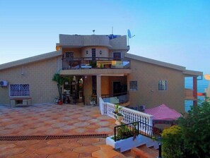 A two-story building with a balcony, a covered outdoor seating area, and a view of the sea. - Seaside Suites and Hotel Room #101 (Freetown)