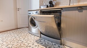 A modern kitchen with a built-in washing machine, patterned floor tiles, and a white door.