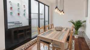 Un espace repas comprenant une table en bois, des chaises et des luminaires suspendus.