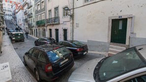 Une rue étroite, bordée de voitures garées et d’immeubles des deux côtés.