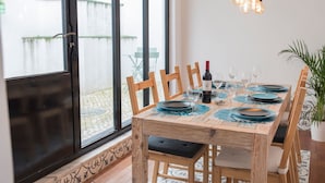 Ein Essbereich mit einem Holztisch, gedeckt für vier Personen, einer Flasche Rotwein und einem Blumentopf.