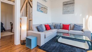A modern living room with a grey sectional sofa, a glass coffee table, and a blue accent piece.