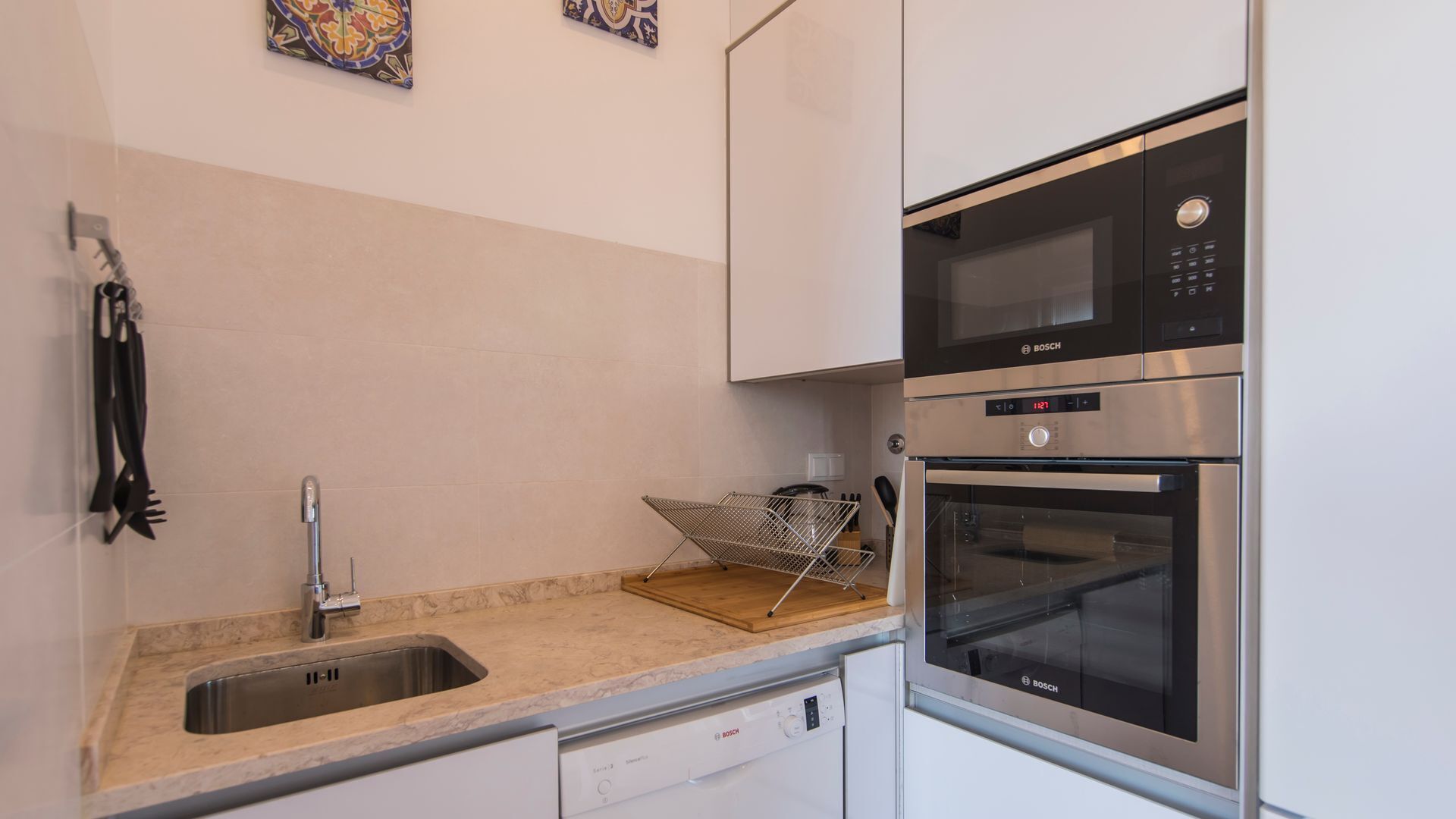 A compact kitchen with a Bosch dishwasher, oven, and microwave.