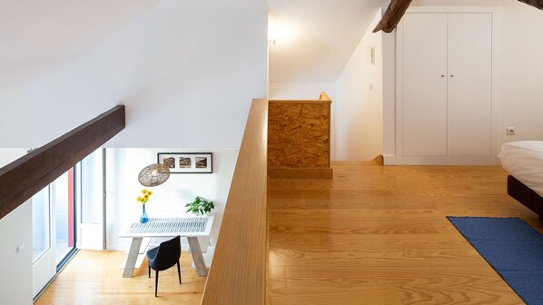 A modern bedroom with a wooden floor, a bed, a desk with a chair, and a small plant. - Oren Duke's House by LovelyStay (Porto)