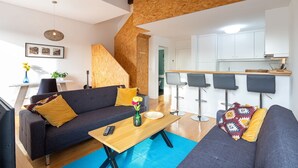 A modern living room with a sofa, coffee table, and bar stools. - Oren Duke's House by LovelyStay (Porto)
