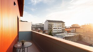 A balcony with a table and chairs, overlooking a cityscape with various buildings. - Oren Duke's House by LovelyStay (Porto)