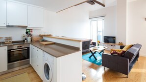 A modern kitchen with a washing machine, a dining area with a sofa, and a TV. - Oren Duke's House by LovelyStay (Porto)