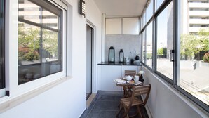 A narrow kitchen with a black countertop, two wooden chairs, and a small table. There are two black lanterns on the wall above the counter.