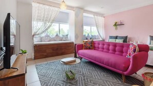 Una sala de estar moderna con un sofá rosa, un banco de madera y una televisión.