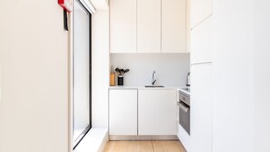 Eine moderne Küche mit weißen Schränken, einer Edelstahl-Spüle und einem eingebauten Backofen.