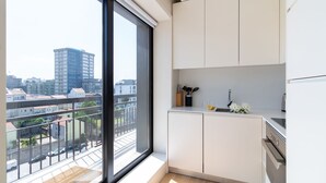 Eine moderne Küche mit weißen Schränken, einer Spüle und einem Fenster mit Blick auf eine Stadtlandschaft.