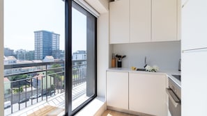 Eine moderne Küche mit weißen Schränken, einer Spüle und einem Fenster mit Blick auf eine Stadtlandschaft.