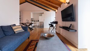 A modern living room with a blue sofa, a coffee table, and a TV mounted on the wall.