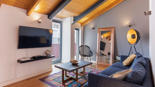 A modern living room with a flat-screen TV, a coffee table, a sofa, and a chair.
