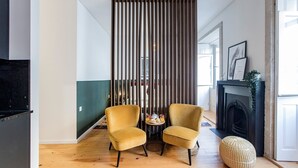 A modern living room with two yellow armchairs, a fireplace, and a wooden floor. - Mouzinho Studio w/ AC in City Center by LovelyStay (Porto)