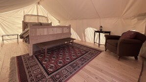 A tent with a bed, a small table, a chair, and a patterned rug. - Luxury Glamping Tent in Moab | Sleeps 2 (Moab)