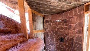 A rustic wooden staircase leading to a stone-walled bathroom with a shower area. - Luxury Glamping Tent in Moab | Sleeps 2 (Moab)