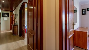 Un pasillo con puertas de madera, un armario de madera y cuadros en las paredes.