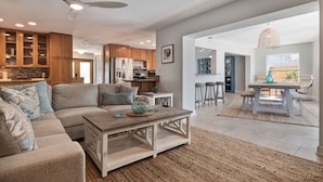 A spacious living room with a sofa, coffee table, and a dining area with a table and chairs. - 511 Harbor Hideaway – Waterfront Retreat w/ Heated Pool, Dock, Golf Cart & Walk to Beach (Indian Rocks Beach)