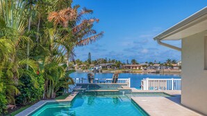 A swimming pool with a view of a body of water and houses in the background. - 511 Harbor Hideaway – Waterfront Retreat w/ Heated Pool, Dock, Golf Cart & Walk to Beach (Indian Rocks Beach)