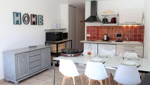 A compact kitchen with a dining area, featuring a microwave, toaster, and a coffee maker on the countertop.