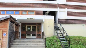 A building entrance with a sign reading "PELVOUX I", a staircase leading up to the entrance, and a no parking sign visible on the left.