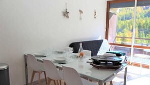 A dining area with a table set for four, a bottle of water, and a portable stove.