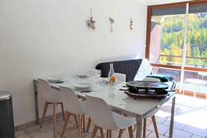 A dining area with a table set for four, a bottle of water, and a portable stove.