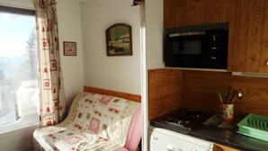 Une cuisine de taille réduite équipée d’un four à micro-ondes, d’une cuisinière et de meubles de rangement en bois.