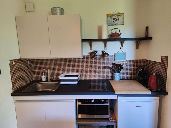 A compact kitchen with a sink, stove, and a small refrigerator.