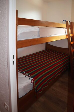 A bunk bed with a striped blanket and a wooden ladder.