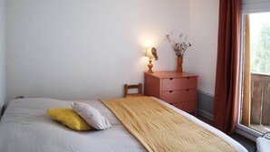 A bedroom with a bed, a bedside table with a lamp, and a window with curtains.