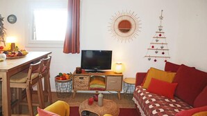 A cozy living room with a TV, wooden furniture, a fruit bowl, and a wall decoration.