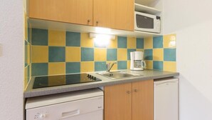 A compact kitchen with a microwave, coffee maker, and dishwasher. - 100m from ski slopes, 5th floor, view mountain, swimming pool, balcony, tv, ski locker, 31m² (Le Corbier)