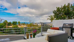 Eine Dachterrasse mit einer Sitzecke, Grill und Blick auf die Landschaft.