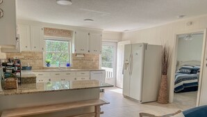 Une cuisine avec des meubles blancs, un plan de travail en granit et un réfrigérateur encastré.