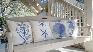 Une balançoire blanche à suspendre, dotée de quatre coussins aux motifs marins.