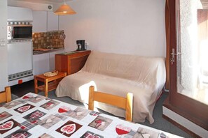 Ein kleines Zimmer mit Bett, Tisch, Küchenzeile und Fenster.