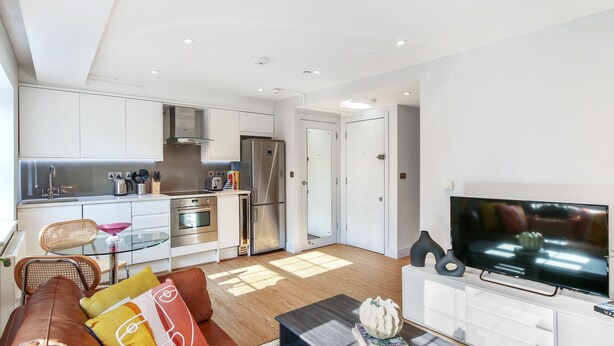 A modern apartment with a kitchen, living area, and a TV. - Cleveland Street by Aeria Apartments (London)