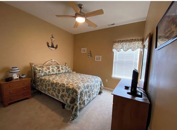 A bedroom with a bed, a nightstand, a desk, a ceiling fan, and a window with blinds. - Cozy 3 bedroom condo, just 2 blocks from the boardwalk (Wildwood)