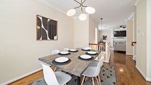 Ein Essbereich mit Holztisch, weißen Stühlen und einer modernen Deckenleuchte.