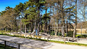 A park with a paved walkway, benches, and playground equipment. - Our attractive vacation apartment for 2 people with excellent facilities. (Prerow)
