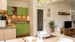 A modern kitchen with green cabinets, a coffee machine, and a dining area with a table set for two. - Our attractive vacation apartment for 2 people with excellent facilities. (Prerow)