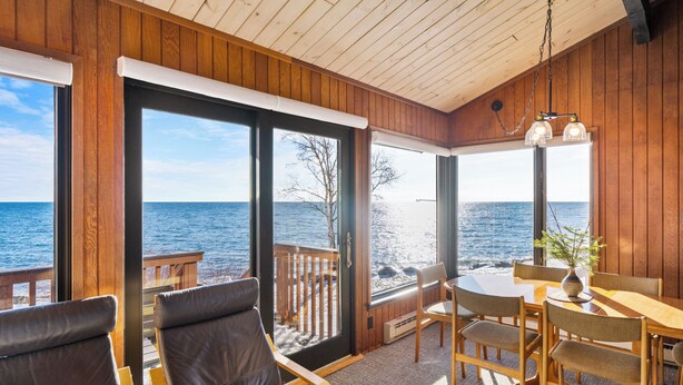 Une terrasse en bois avec une table et des chaises, une vue sur l’océan et un plafond en bois.