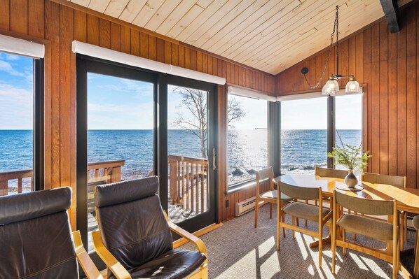 A wooden deck with a table and chairs, a view of the ocean, and a wooden ceiling. - Lutsen Sea Villas (Lutsen)