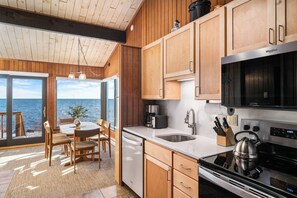 A modern kitchen with wooden cabinets, a stainless steel stove, and a large window overlooking the sea. - Lutsen Sea Villas (Lutsen)